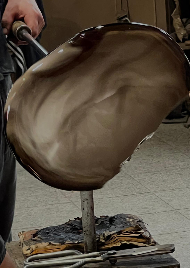 Glass being formed in the workshop — molten on the punty